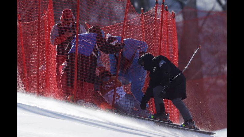 Officials assist Russian skier Pavel Trikhichev after he crashed in the downhill portion of the men's combined.