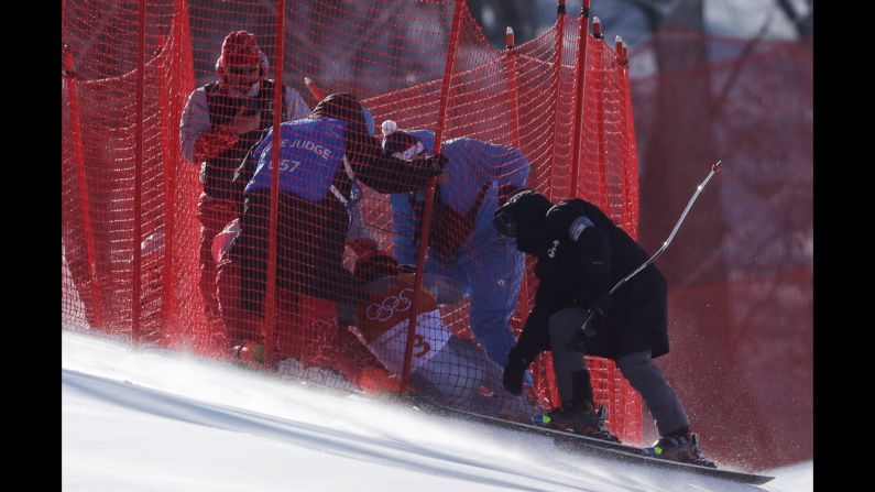 Officials assist Russian skier Pavel?Trikhichev after he crashed in the downhill portion of the men's combined.