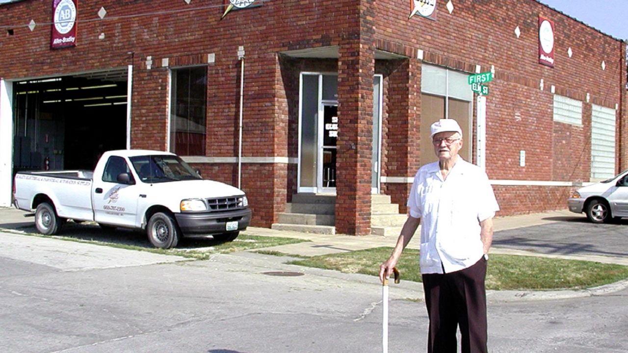 Richard Rohwedder stands in front of the red brick building where his father's bread slicing machine was put into use in July 1928.