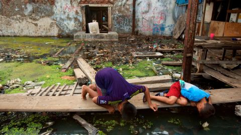 Boys look for snakes in standing water in an abandoned factory, November 24, 2015 in Jakarta, Indonesia.  