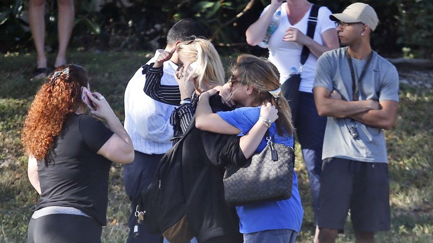 Anxious family members wait for news of students as two people embrace, Wednesday, Feb. 14, 2018, in Parkland, Fla. A shooting at Marjory Stoneman Douglas High School sent students rushing into the streets as SWAT team members swarmed in and locked down the building. (AP Photo/Wilfredo Lee)