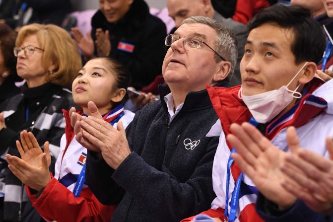 Thomas Bach, president of the International Olympic Committee, sits between the North Korean figure skating duo of Ryom Tae Ok and Kim Ju Sik.