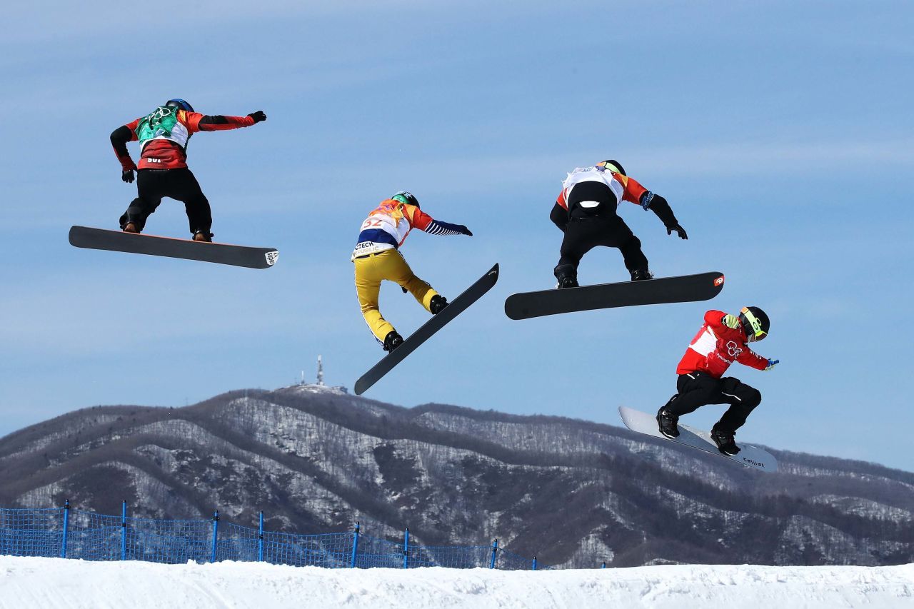 Athletes race in a snowboard cross quarterfinal.