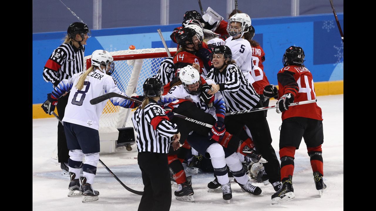 An official tries to separate players from Canada and the United States during a preliminary round hockey game. Canada won 2-1.