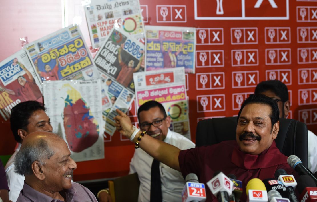 Former Sri Lankan president Mahinda Rajapakse holds a newspaper displaying areas where his party won local government seats during a press conference in Colombo on February 12, 2018.
