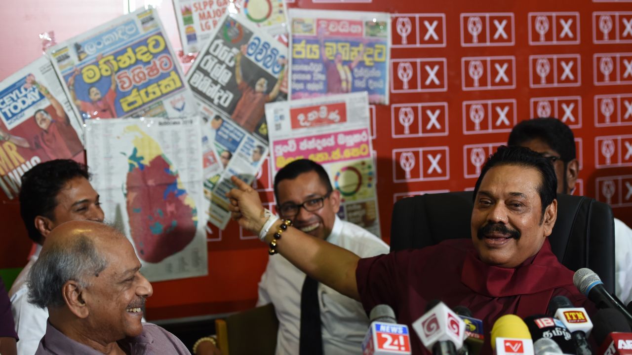 Former Sri Lankan president Mahinda Rajapakse holds a newspaper displaying areas where his party won local government seats during a press conference in Colombo on February 12, 2018.
