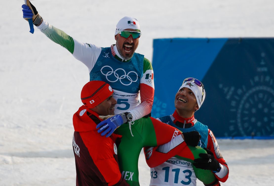 German Madrazo sits on the shoulders of Taufatofua and Azzimani as they celebrate finishing the 15km cross country freestyle.
