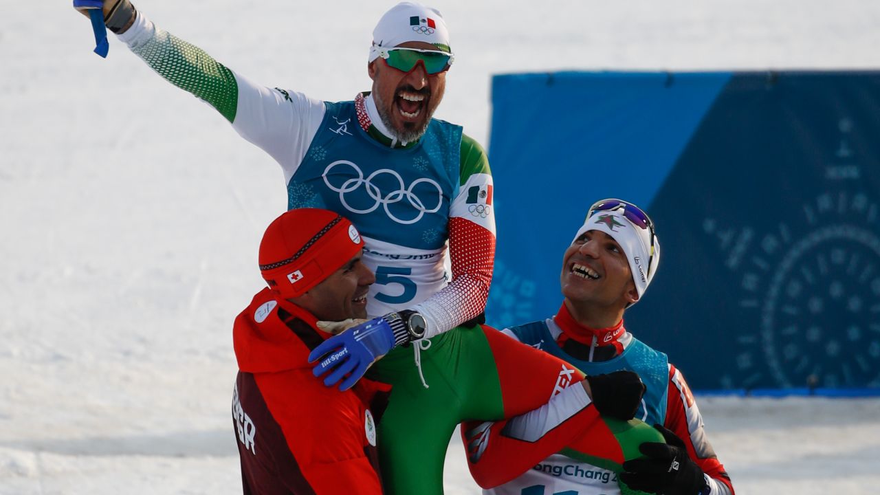 German Madrazo sits on the shoulders of Taufatofua and Azzimani as they celebrate finishing the 15km cross country freestyle.