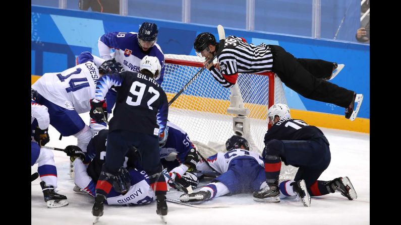 A referee jumps onto the net to avoid play during the hockey game between Slovakia and the United States.