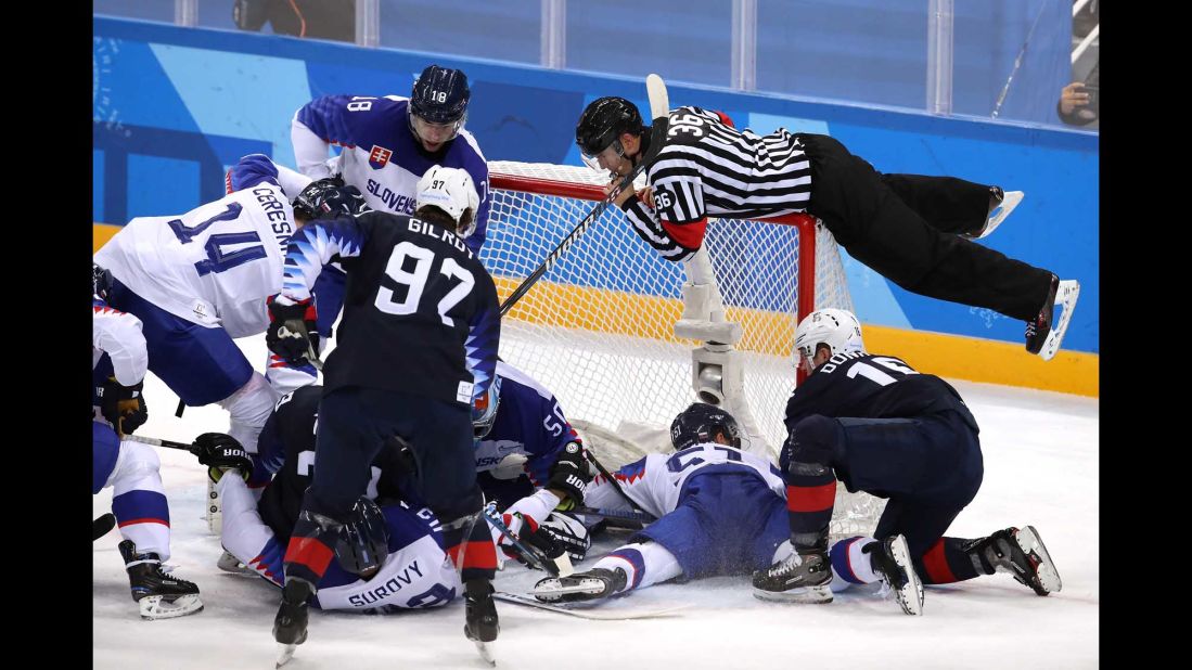 A referee jumps onto the net to avoid play during the hockey game between Slovakia and the United States.