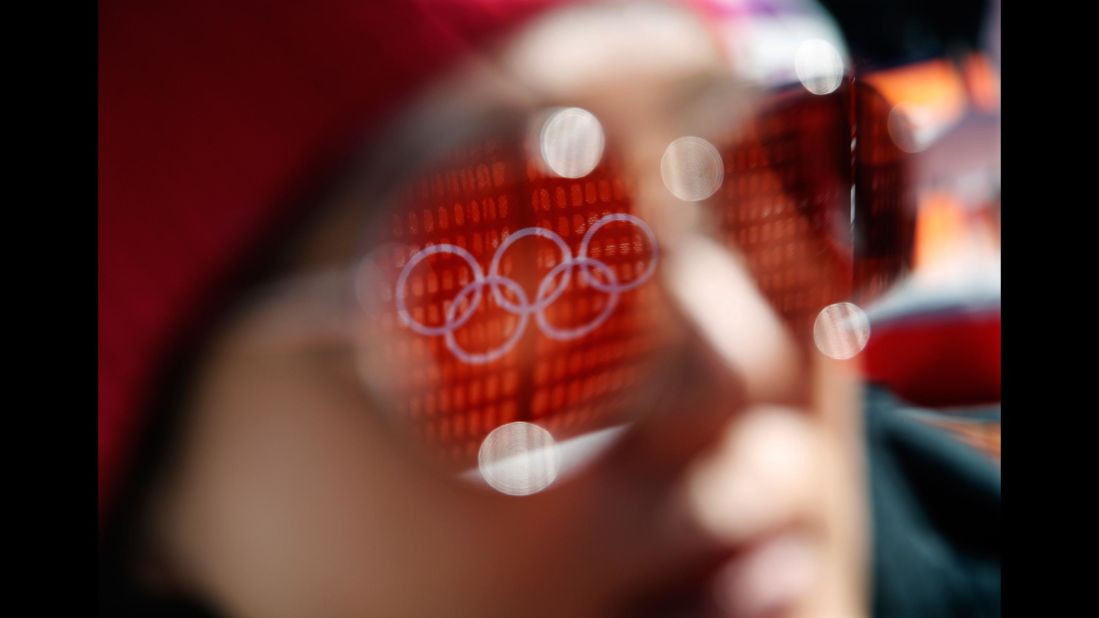 The Olympic rings are reflected in a spectator's sunglasses before the start of the women's super-G.