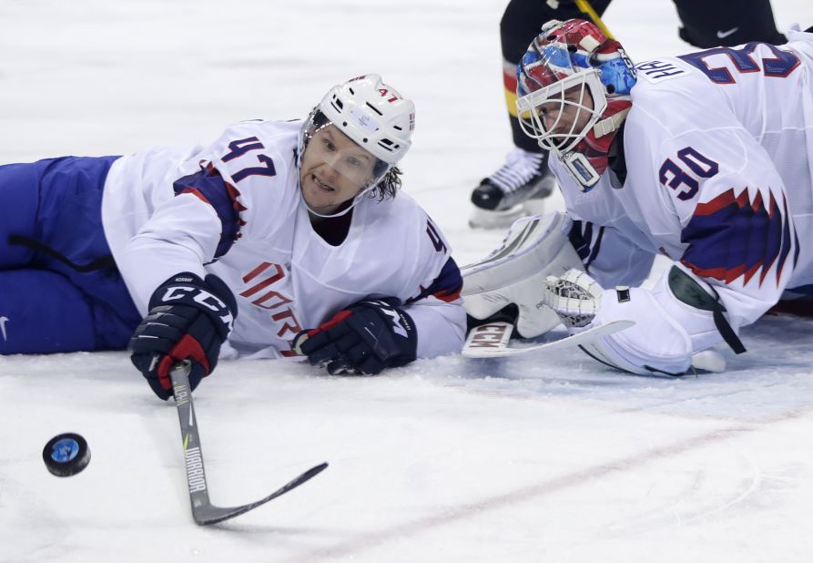 Alexander Bonsaksen and goalie Lars Haugen of Norway reach for the puck during the second period of the preliminary round of their hockey game against Germany.