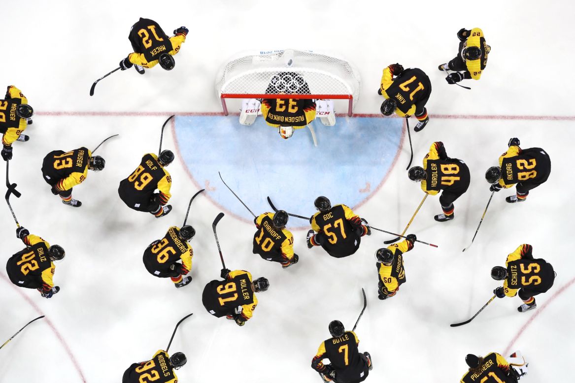 The German team huddles around the net before their game against Norway during the men's ice hockey preliminary round.