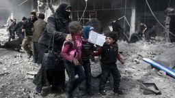 A Syrian woman and children run for cover amid the rubble of buildings following government bombing in the rebel-held town of Hamouria, in the besieged Eastern Ghouta region on the outskirts of the capital Damascus, on February 19, 2018.
Heavy Syrian bombardment killed 44 civilians in rebel-held Eastern Ghouta, as regime forces appeared to prepare for an imminent ground assault. / AFP PHOTO / ABDULMONAM EASSA        (Photo credit should read ABDULMONAM EASSA/AFP/Getty Images)