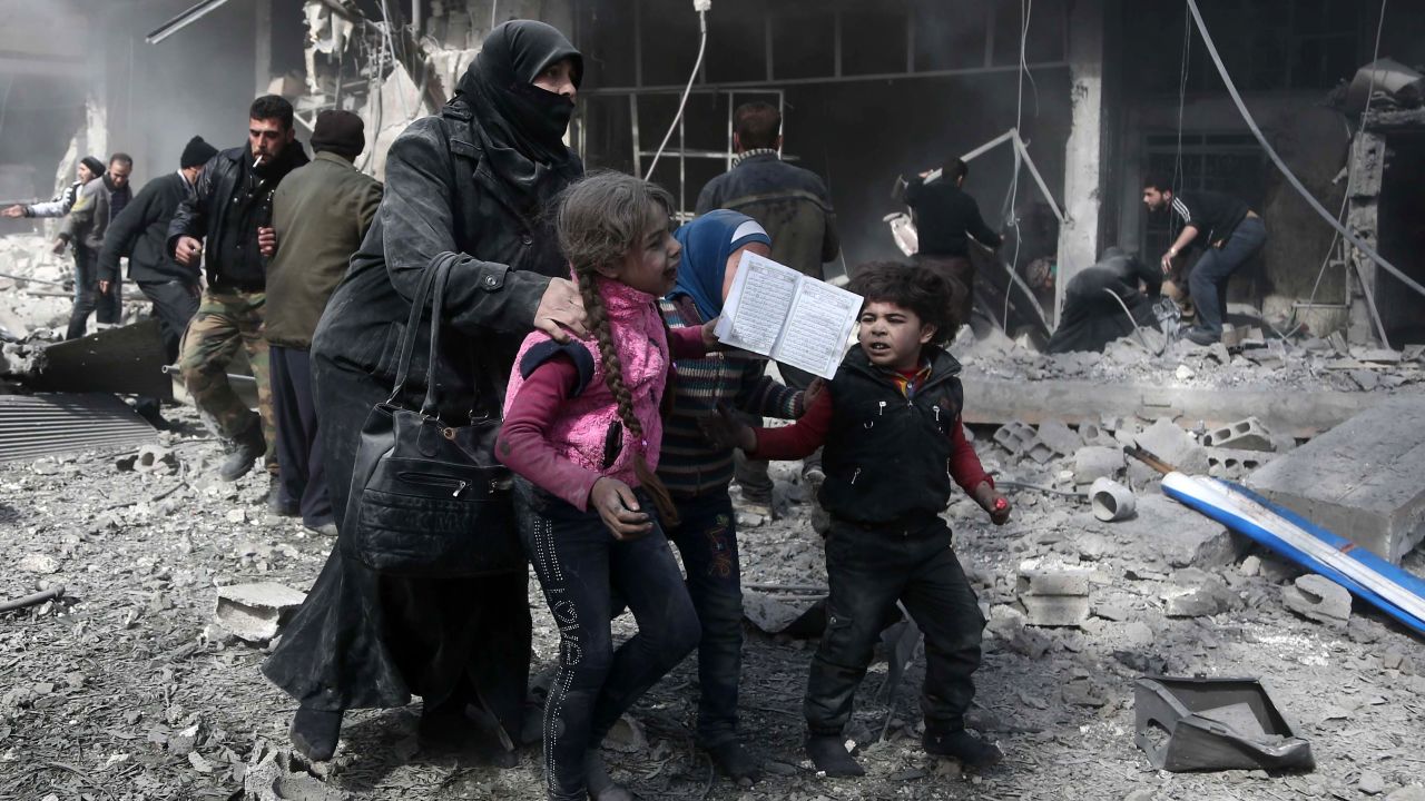 A Syrian woman and children run for cover in Hamouria, in the Eastern Ghouta region.