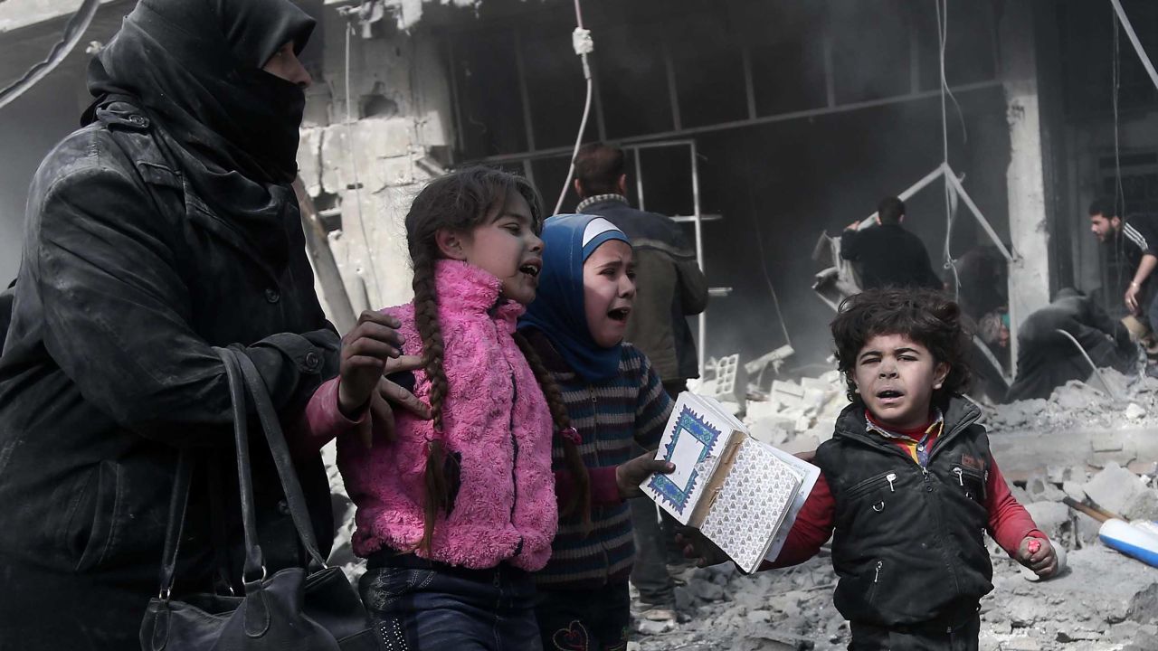 A Syrian woman and children run for cover amid the rubble of buildings following government bombing in the rebel-held town of Hamouria, in the besieged Eastern Ghouta region on the outskirts of the capital Damascus, on February 19, 2018.
Heavy Syrian bombardment killed 44 civilians in rebel-held Eastern Ghouta, as regime forces appeared to prepare for an imminent ground assault. / AFP PHOTO / ABDULMONAM EASSA        (Photo credit should read ABDULMONAM EASSA/AFP/Getty Images)