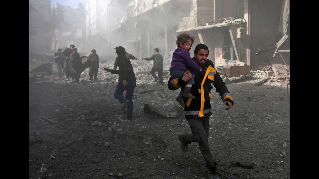 A man carries an infant he rescued from the rubble in Hamouria on February 19.