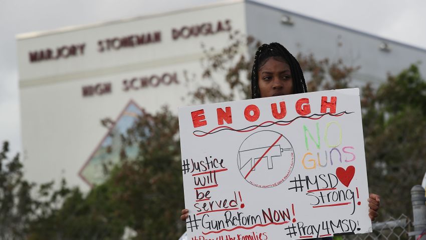 PARKLAND, FL - FEBRUARY 20:  Tyra Heman, a senior at Marjory Stoneman Douglas High School, holds a sign that reads, 'Enough No Guns,' in front of the school where 17 people that were killed on February 14, on February 19, 2018 in Parkland, Florida. Police arrested 19-year-old former student Nikolas Cruz for killing 17 people at the high school.  (Photo by Joe Raedle/Getty Images)