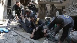 Members of a Syrian civil defence team rescue a man following a reported regime air strike in the rebel-held town of Hamouria, in the besieged Eastern Ghouta region on the outskirts of the capital Damascus on February 21, 2018.  / AFP PHOTO / ABDULMONAM EASSA        (Photo credit should read ABDULMONAM EASSA/AFP/Getty Images)