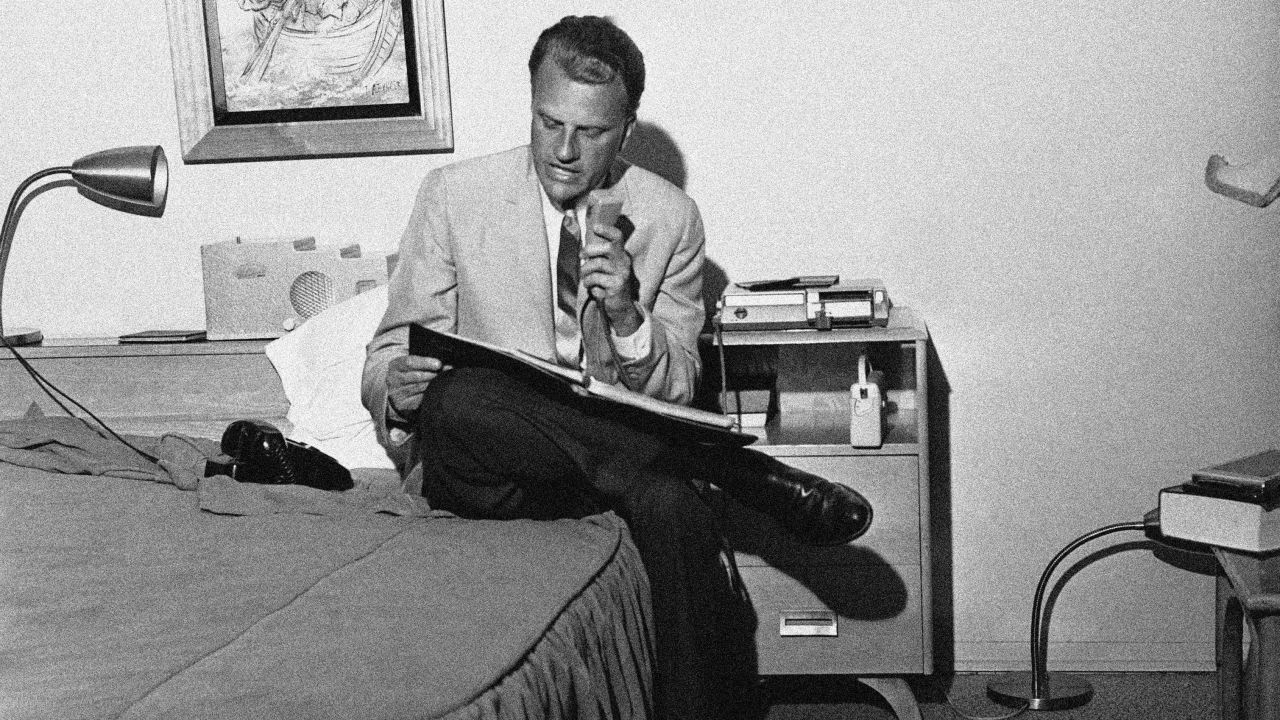 Graham dictates a synopsis of his evening sermon into a tape recorder in 1962. Secretaries would then type the synopsis for distribution to the press. Graham was conducting an eight-day crusade in Fresno, California.