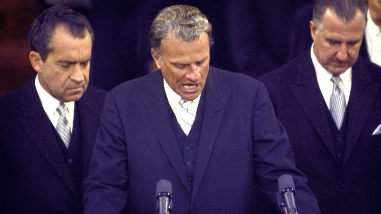 Graham is flanked by US President Richard Nixon, left, and Vice President Spiro Agnew as they bow their heads in prayer in 1969. Graham was speaking at Nixon's inauguration.