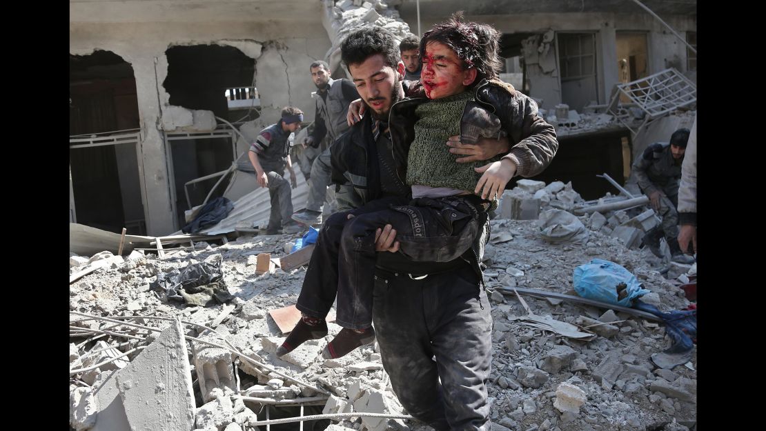 A man rescues a child after a reported regime airstrike in Hamurriya, Eastern Ghouta, on Wednesday.