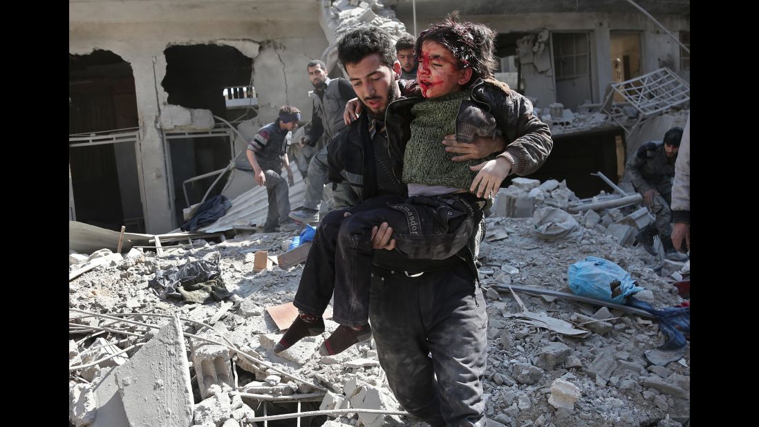 A man rescues a child after a reported airstrike in the rebel-held town of Hamouria on Wednesday, February 21. Syria says it is targeting terrorists in Eastern Ghouta.