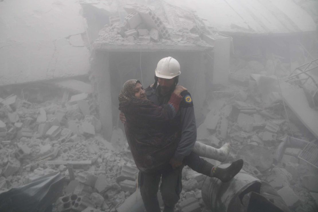 A rescue worker carries a woman from the wreckage of buildings hit by an airstrike over Erbin in Eastern Ghouta on Tuesday.