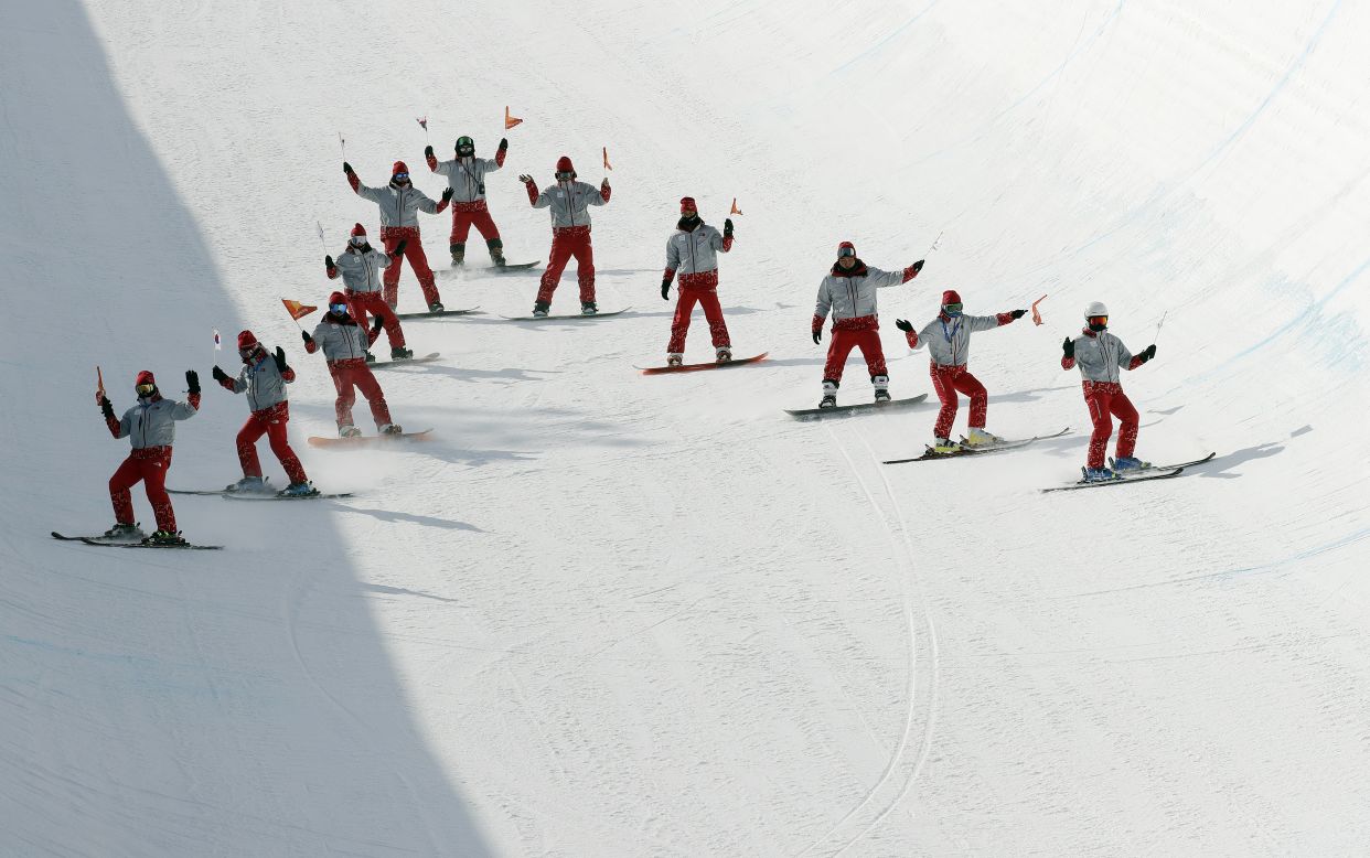 Volunteers prepare the course in between runs for the ski halfpipe.