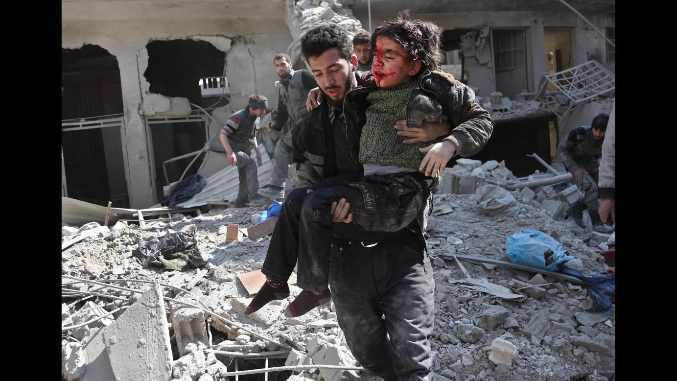 A man rescues a child after a reported regime airstrike in the rebel-held town of Hamouria in Syria's <a href="https://edition.cnn.com/2018/02/21/middleeast/syria-eastern-ghouta-bombardment-intl/index.html" target="_blank">besieged Eastern Ghouta</a> region on Wednesday, February 21. As many as 300 people died over three days in the bombardment of the rebel enclave, medics and activists say.