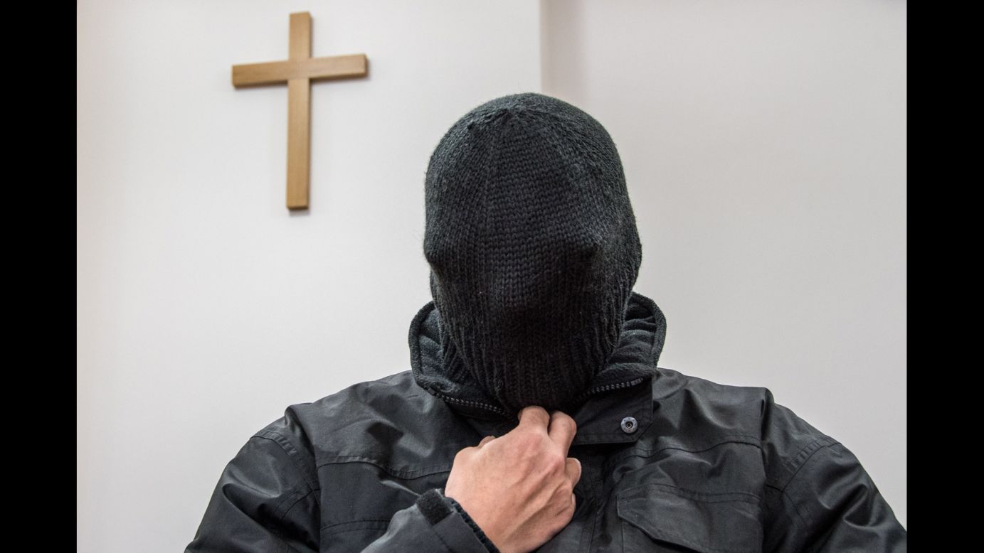 A former priest charged with sexually abusing five boys hides his face in his hat as he waits for his trial at court in Germany on Thursday, February 22.