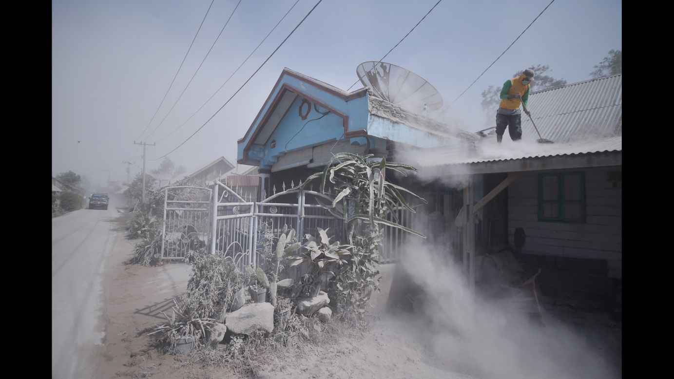 A man cleans debris from the roof of a house on Tuesday, February 20 after Mount Sinabung spewed volcanic ash into the air the day before in Indonesia.