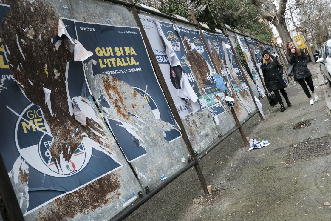 Women walk past  candidates' posters in Rome ahead of Sunday's general elections.