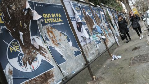 Women walk past  candidates' posters in Rome ahead of Sunday's general elections.