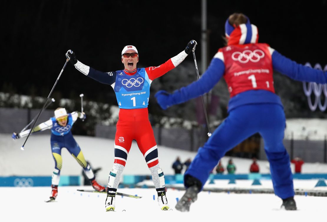 Marit Bjoergen crosses the finish line to win gold with Ingvild Flugstad Oestberg in the women's  4x5km Relay