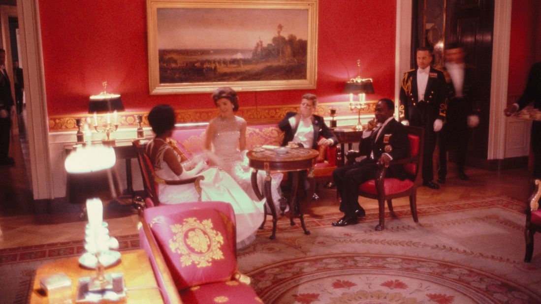 In this photograph President John F. Kennedy, first lady Jacqueline Kennedy, President Félix Houphouët-Boigny of the Ivory Coast, and first lady Marie-Thérèse Houphouët-Boigny of the Ivory Coast converse in the Red Room of the White House. The group was attending a State Dinner held in honor of President Houphouët-Boigny's State Visit on May 22, 1962.