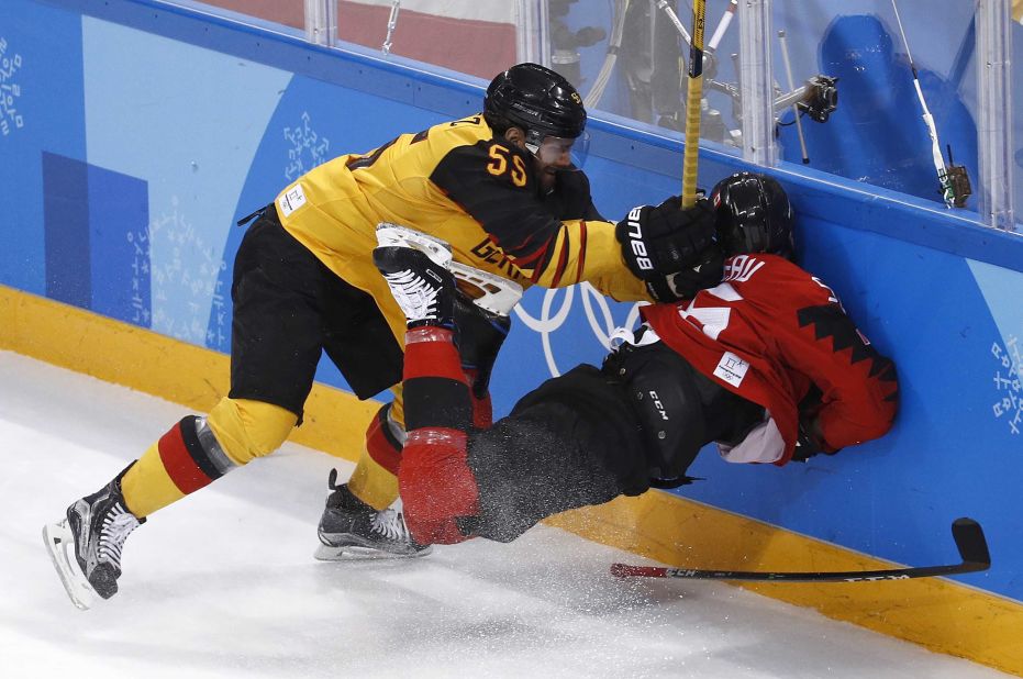 Germany's Felix Schutz checks Canada's Maxim Noreau into the boards during the first period of their semifinal game. Germany won 4-3.