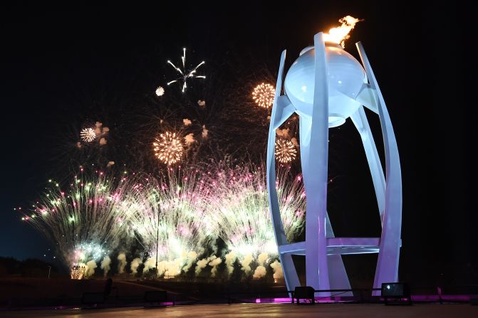 Fireworks explode behind the Olympic flame at the start of the closing ceremony.