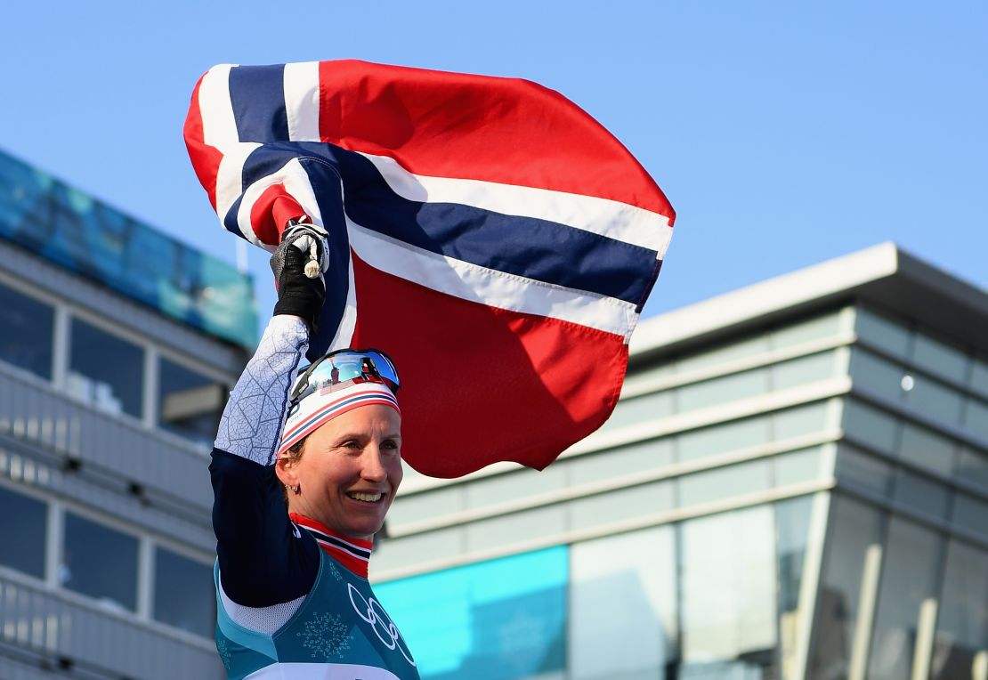 Marit Bjoergen holds aloft the Norwegian flag after winning her eighth Olympic gold medal.