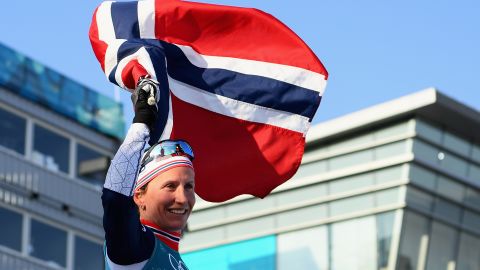 Marit Bjoergen holds aloft the Norwegian flag after winning her eighth Olympic gold medal.