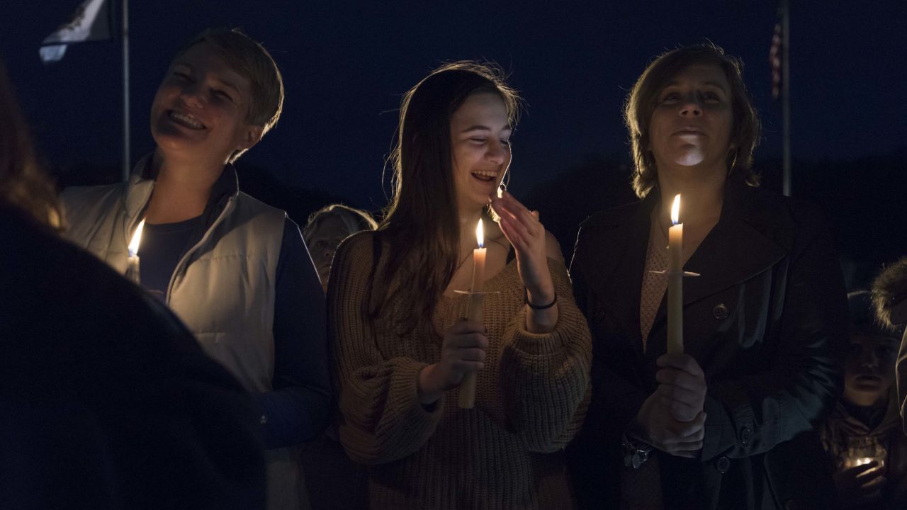 Susie Garrison, left, a teacher at Capital High School, student Amelia Engle from George Washington High School and Nitro High School teacher Kizmet Chandler take part in a candlelight rally in support of the statewide teacher walkout outside of the capitol building in Charleston, West Virginia, on Sunday.