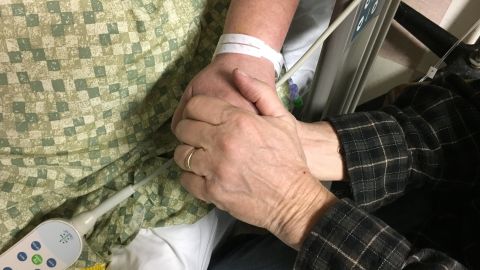 Rosemarie Melanson's hand is held by her husband, Steve, as she remains in the hospital, months after the Las Vegas shooting.