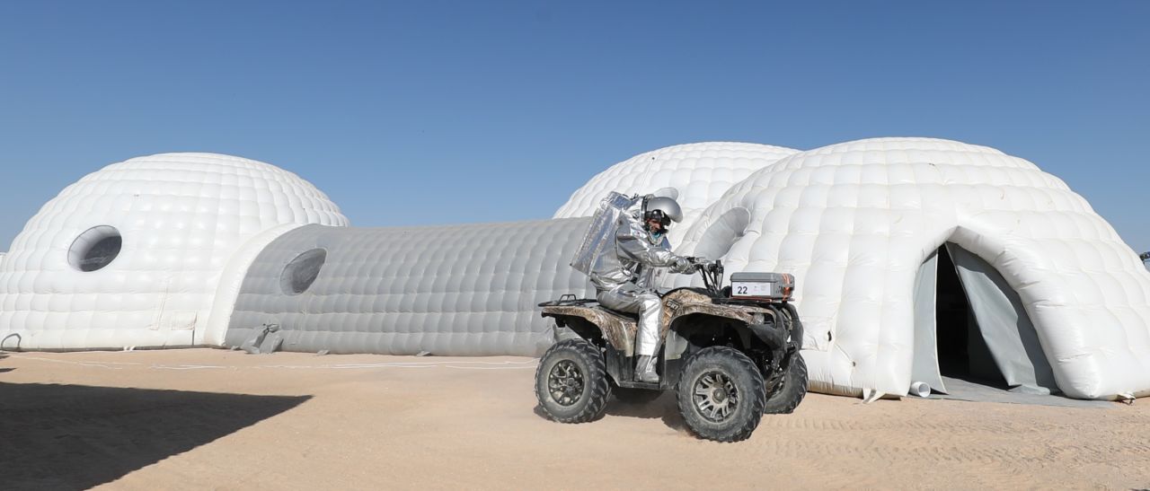 An analog astronaut on a buggy stops outside inflatable residences for members of the AMADEE-18 mission in Oman's Dhofar region.