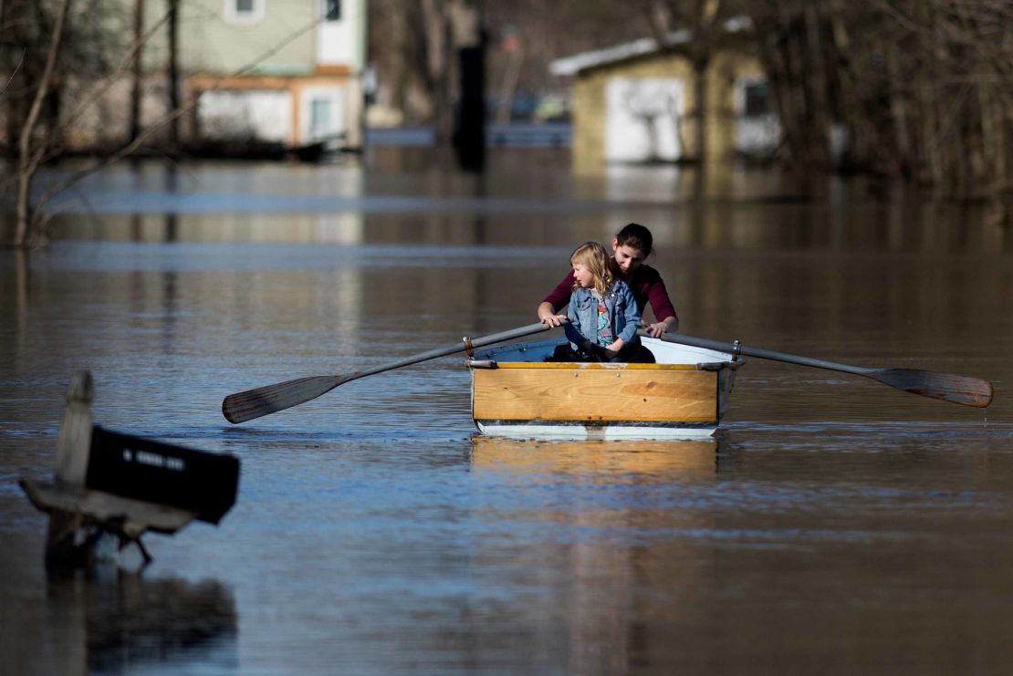 Emily Snyder teaches her daughter, Skyler, 4, how to row a boat as they check out their flooded home in Plainfield Township, Michigan, on Monday.