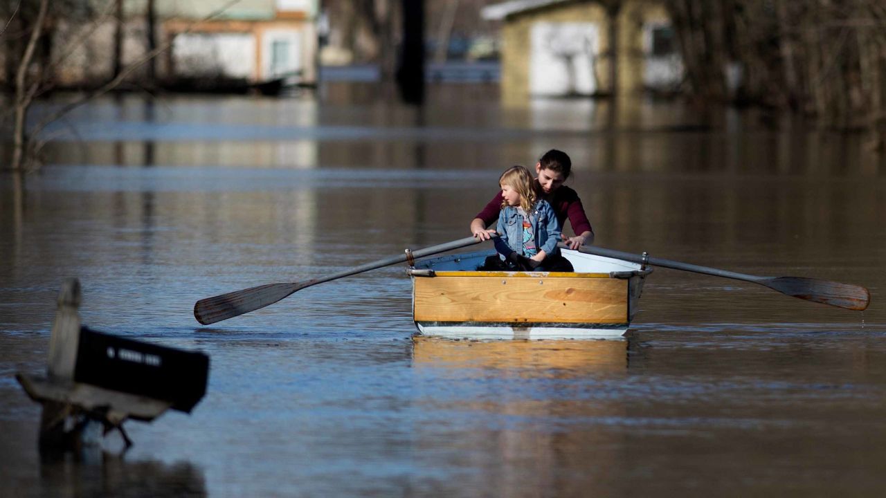 Emily Snyder teaches her daughter, Skyler, 4, how to row a boat as they check out their flooded home in Plainfield Township, Michigan, on Monday.