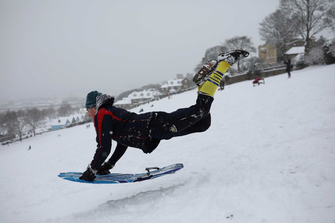  A young man takes a running jump down a snow covered hill with his sled on February 27, 2018 in Rochester, Kent.