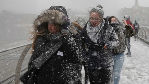 Pedestrians cross the Millennium Bridge as heavy snowfall hits London.