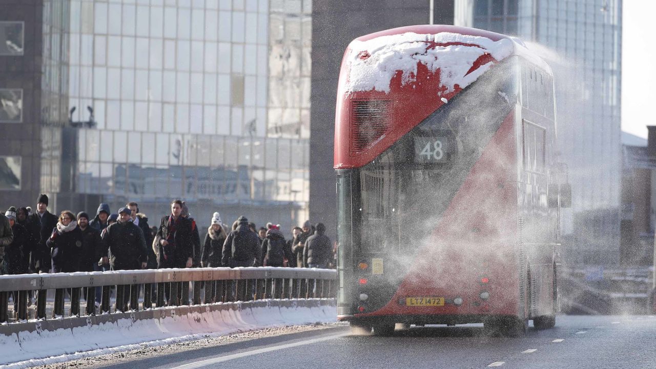 Snow blows off a bus as commuters cross London Bridge after snow hit London overnight.