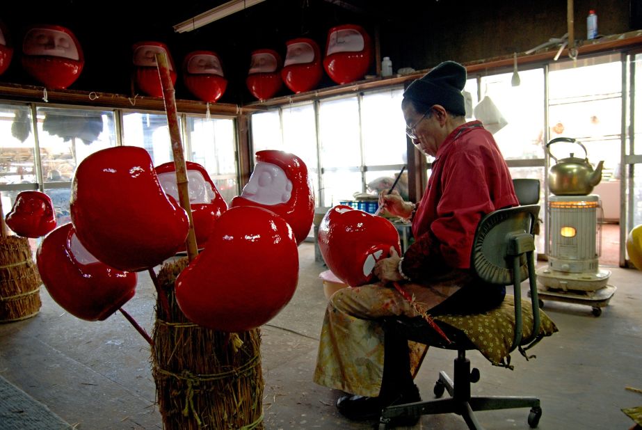Artisans use brushes to paint on the daruma doll's features.