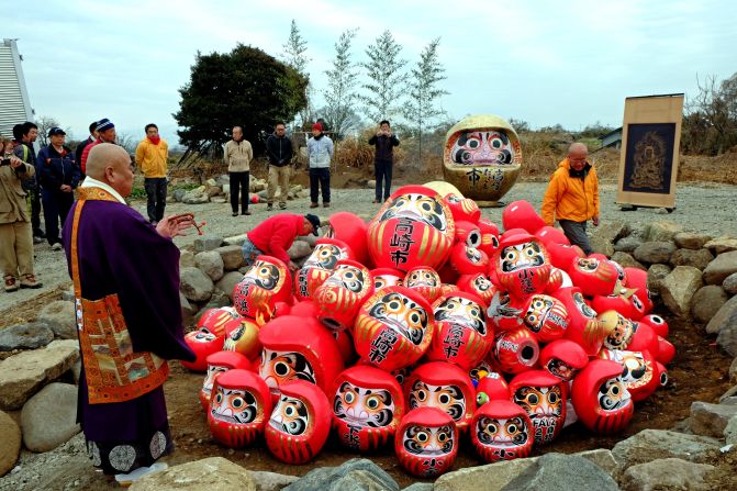 A Buddhist priest prepares to set Daruma dolls alight.